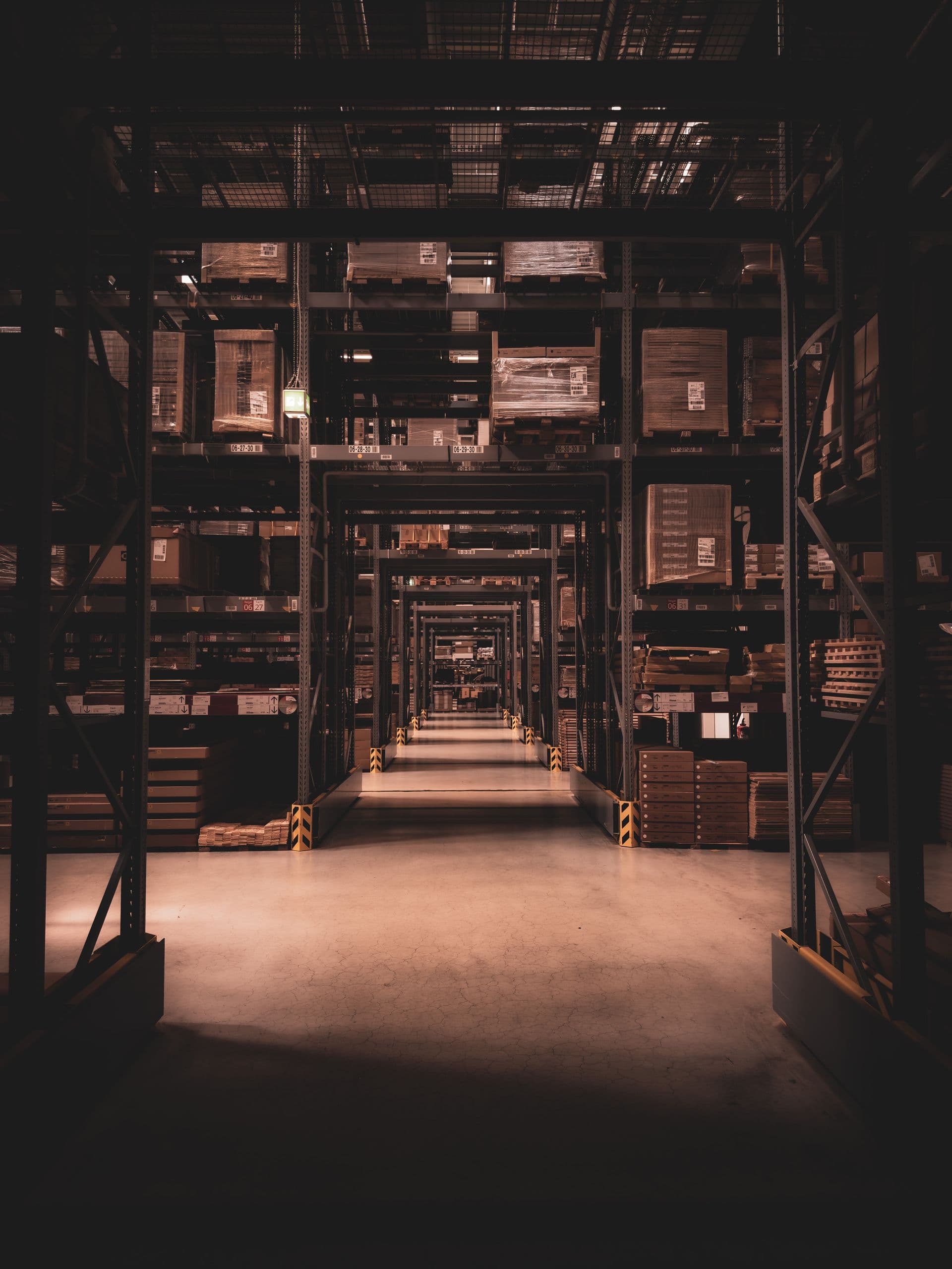 Deep warehouse aisle stacked with pallets, vanishing point perspective
